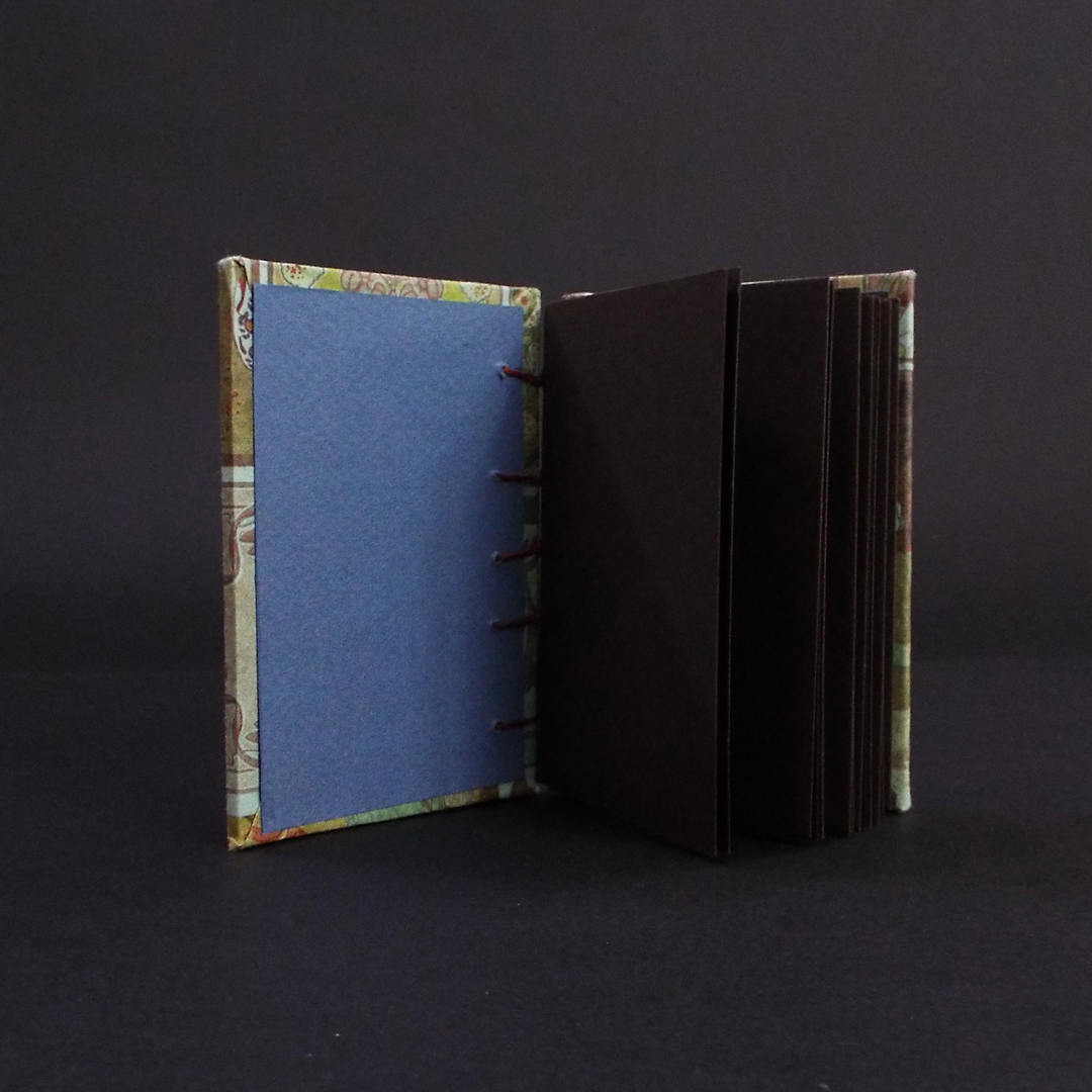 Art nouveau floral coptic bound journal inside showing brown text block pages and navy blue end pages