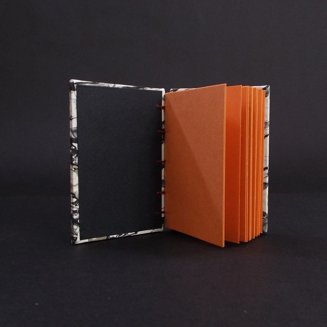 Black marbled mini coptic bound book inside showing orange text block and black end pages