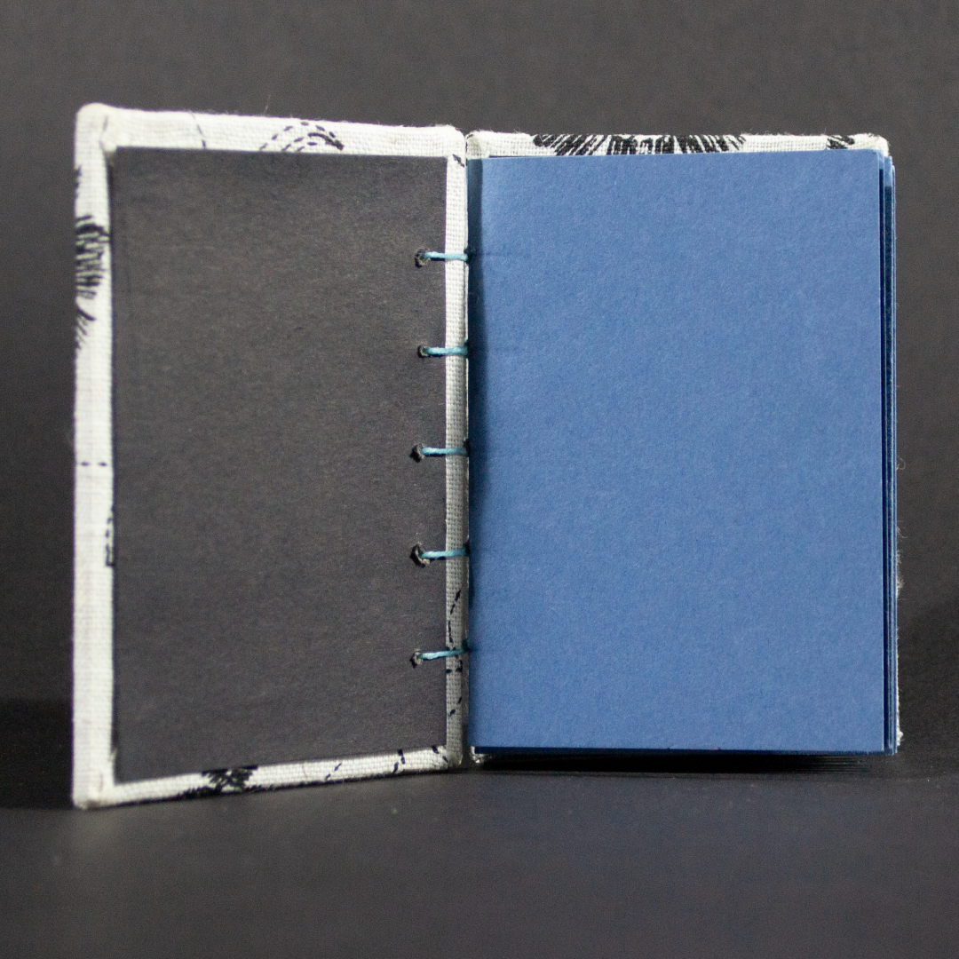 Inside shot of black and white floral mini Coptic book showing blue cardstock pages and black end pages