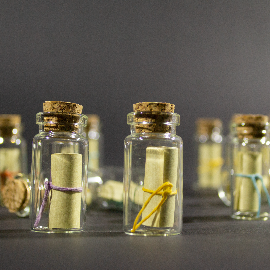 Message in a Bottle product shot with multiple bottles in focus in the foreground. Inside the bottle is a rolled up scroll.