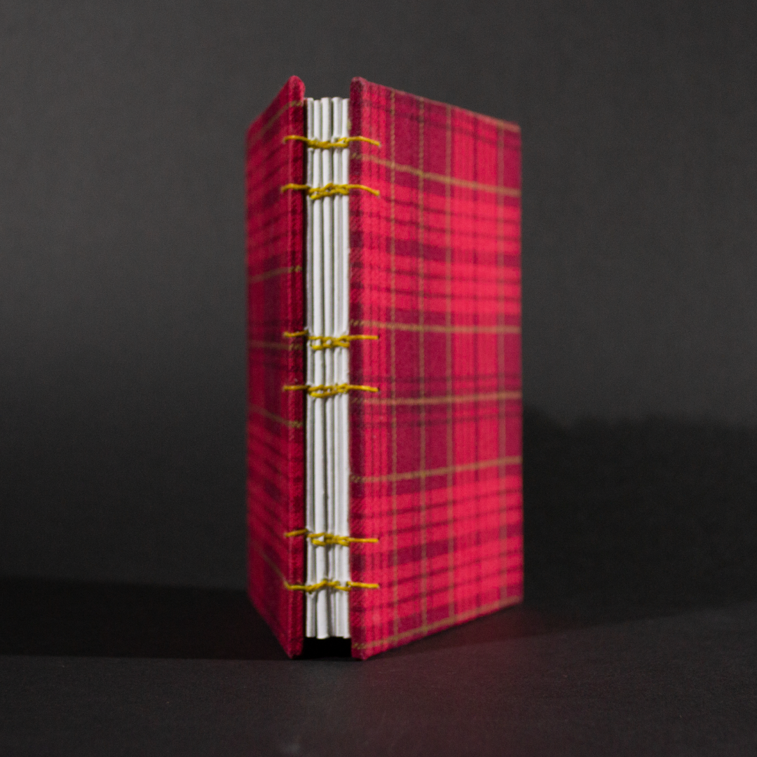 Spine view of red plaid octavo Coptic bound journal with inside white end pages and text pages