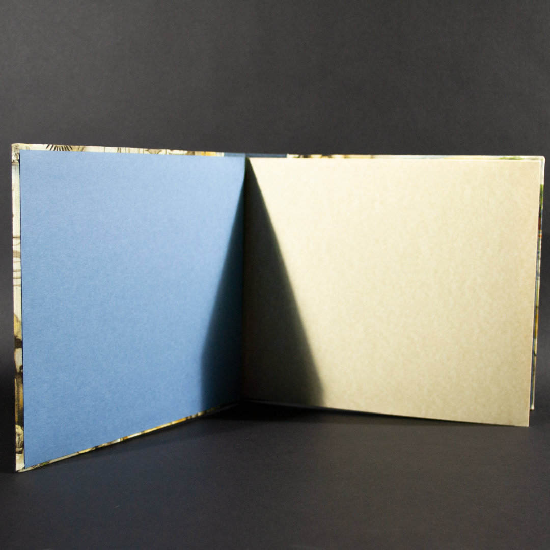 Front cover of stab bound Egyptian photo album showing the blue end pages and ivory card stock inside pages