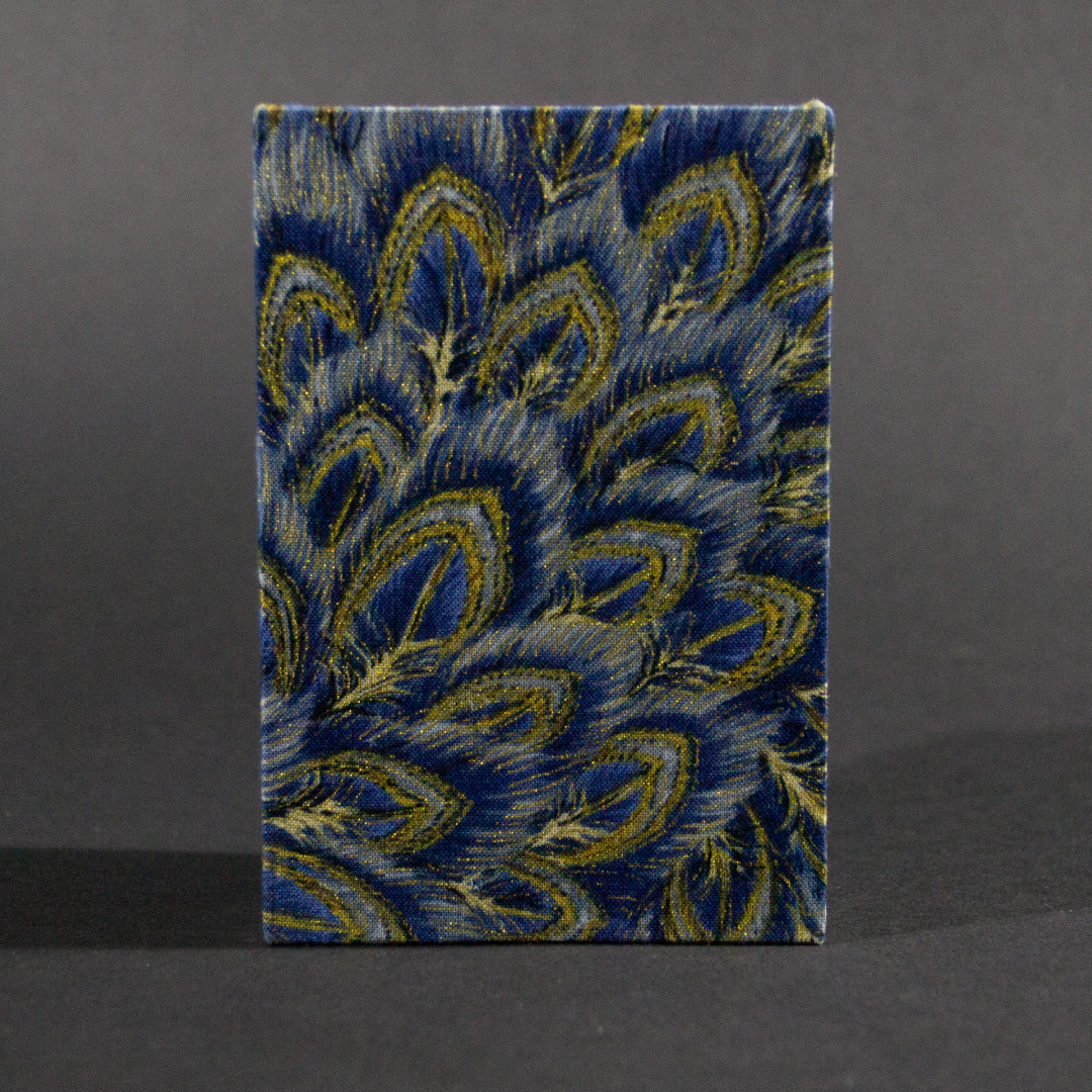 The front cover of the peacock medium accordion book has peacock feathers in blue and gold.