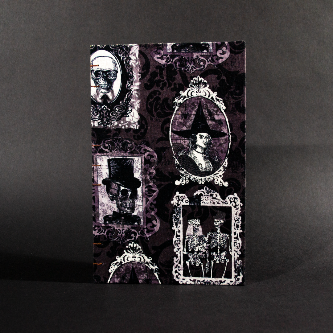 The front cover of the spooky portraits quarto Coptic bound journal features framed witches and skeletons in black and white
