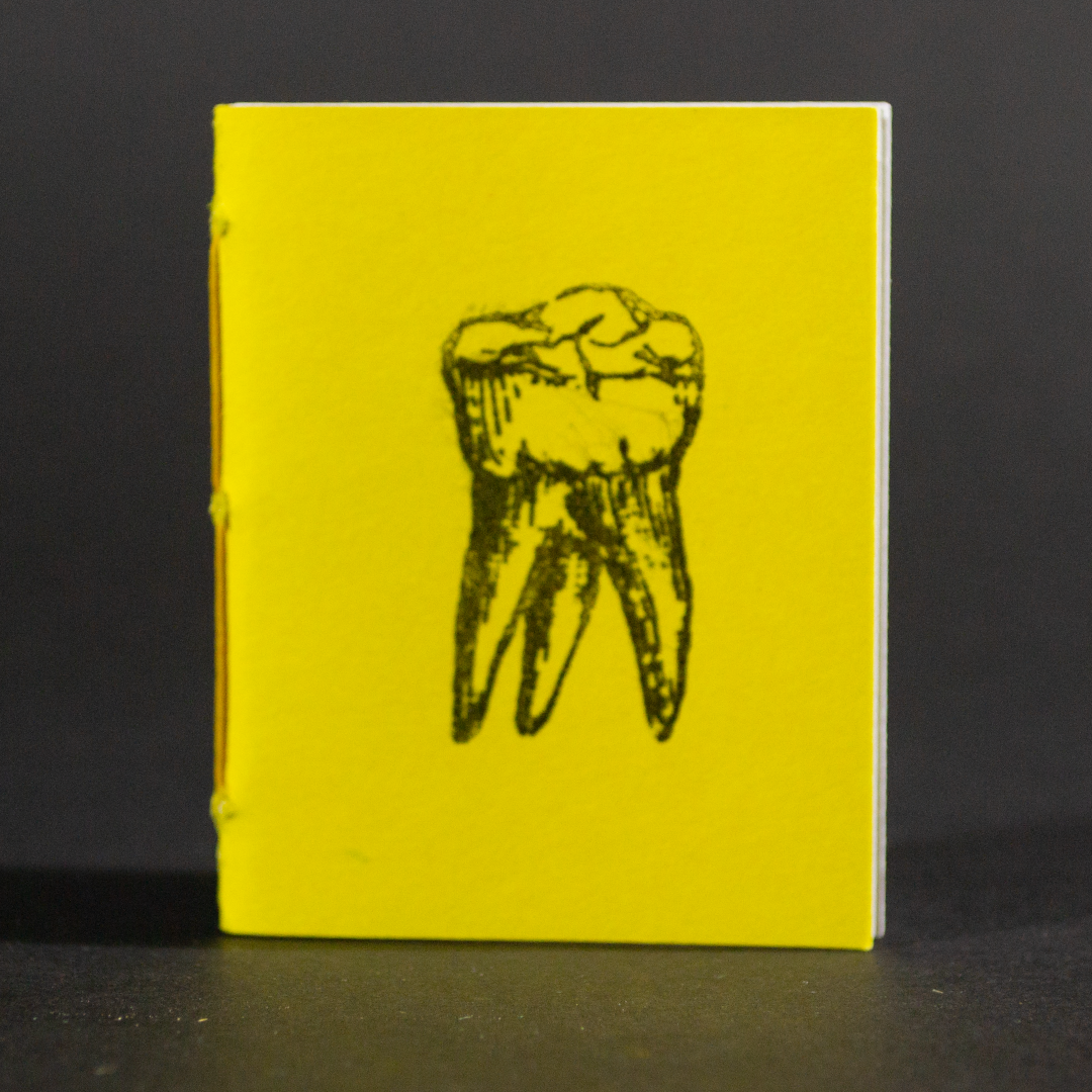 A single yellow tooth is on the cover of this mini pamphlet book